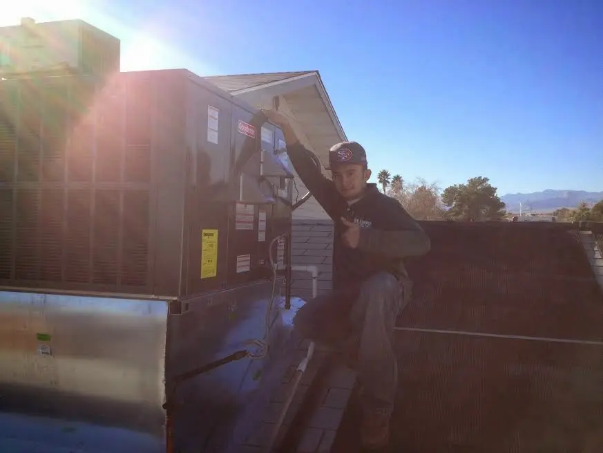 HVAC technician performing Heat Pump Repair on a rooftop unit in Groton